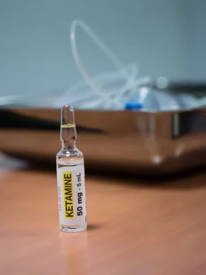 Pharmaceutical bottle of Ketamine Injectable Solution with an accompanying syringe, displayed on a wooden tray, premium product from www.psychedelicdeals.com.