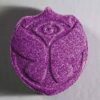 One purple MDMA Pill surrounded by many colorful MDMA Pills also known as molly, premium quality from Psychedelic Deals