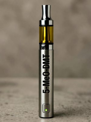 A professional gray 5-MeO-DMT Vape Pen with a clear window showing the concentrated oil, standing upright against a blurred background with 5-MeO-DMT Vape Pens printed in black.
