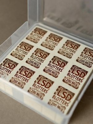 Professional white packaging containing a sheet of LSD Blotters with visible perforated squares and vibrant psychedelic artwork.
